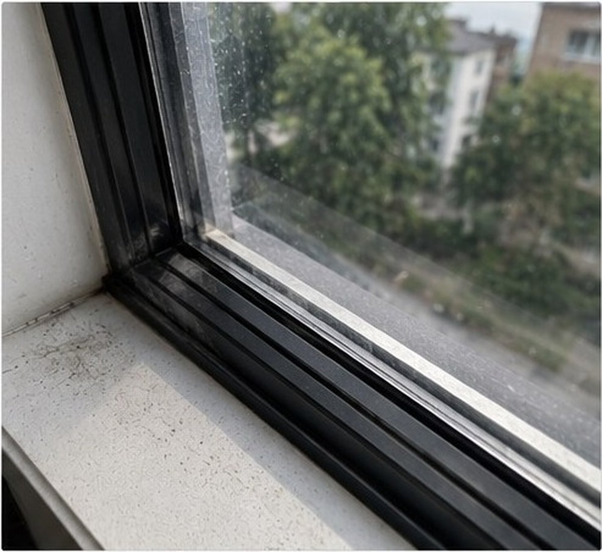 Veca izbalējusi un burbuļojoša plēve uz loga pirms noņemšanas